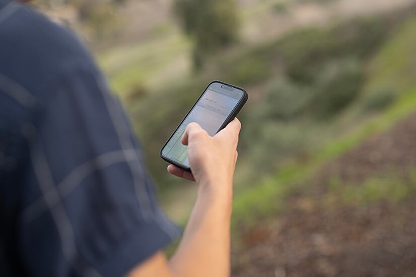 Eversense-användare som står utanför och använder en smartphone för att övervaka sina glukosmönster 