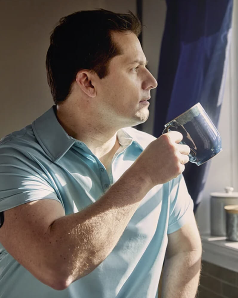 En Eversense CGM-användare med en sändare på armen håller en blå mugg 