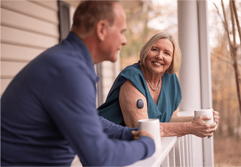 Användare av Eversense CGM-enhet pratar med en man på uteplatsen