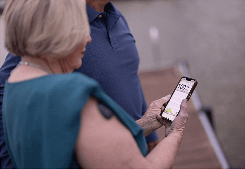 En äldre kvinna tittar på sin smartphone för att övervaka glukosnivåerna