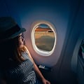 En Eversense-användare reser med CGM-enheten mes en hatt på huvudet, kopplar av och tittar ut genom ett flygplansfönster.